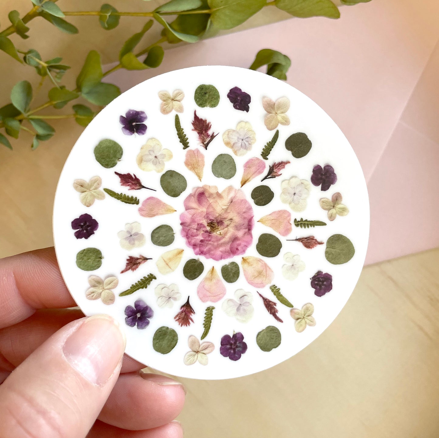 circle sticker mandala design made with pink and purple pressed flowers.