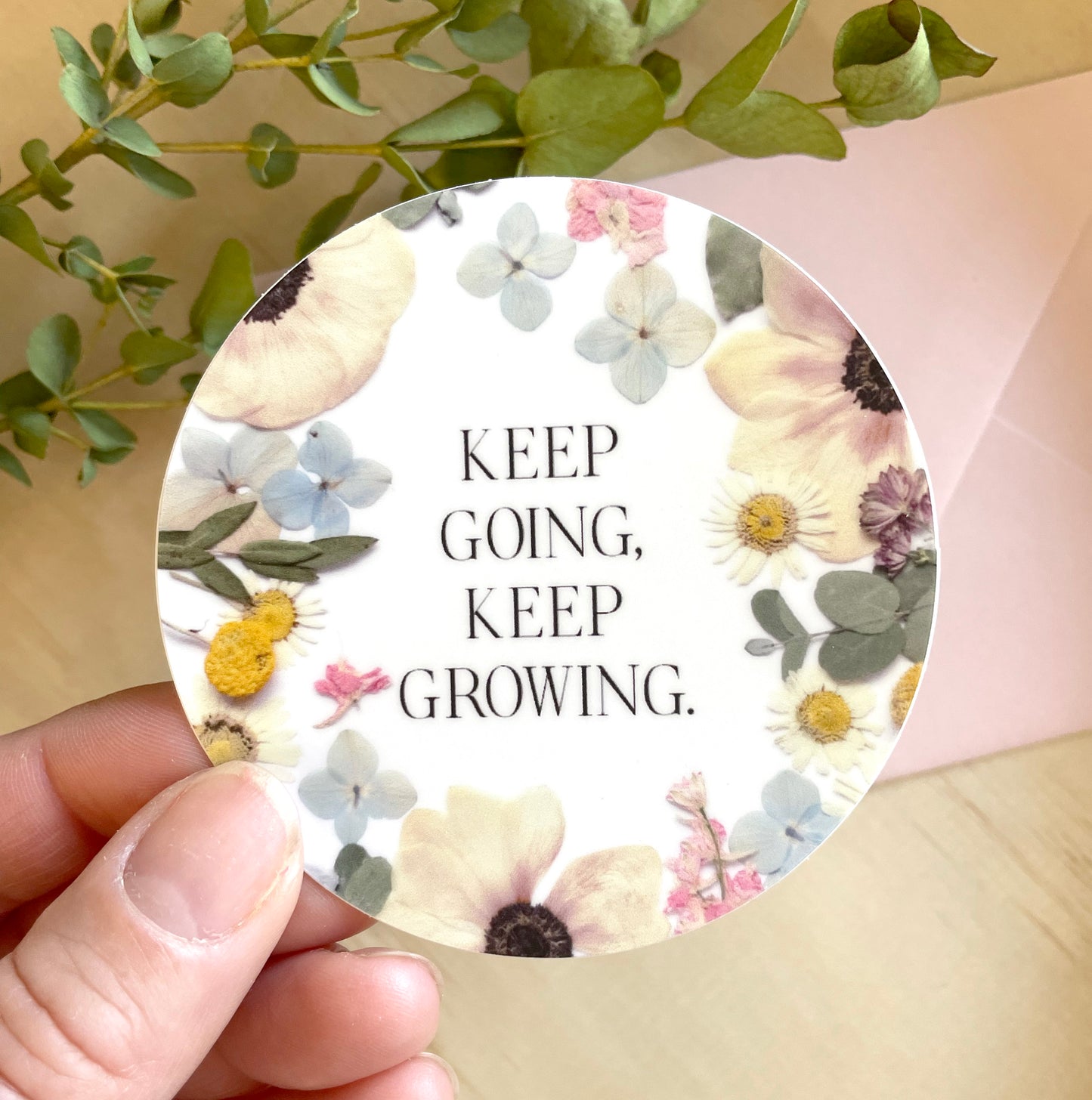 circle sticker of dried pressed flowers with quote keep going, keep growing.