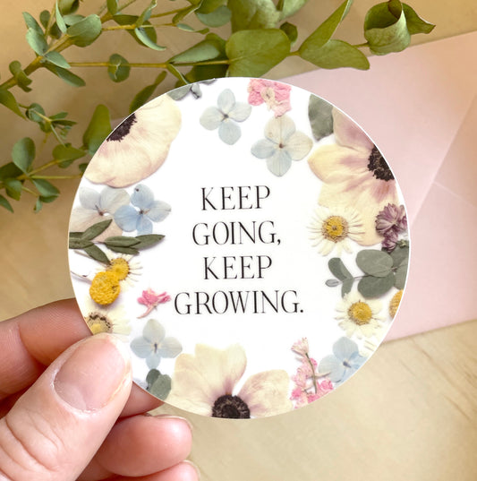 circle sticker of dried pressed flowers with quote keep going, keep growing.