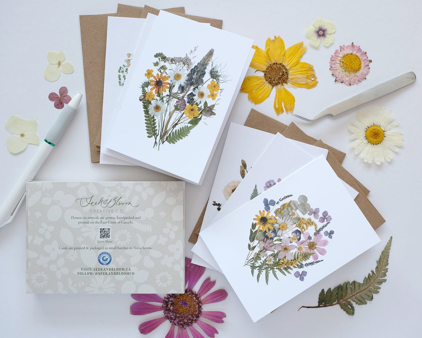 Collection of floral cards and stationery items on a light surface with flowers around.