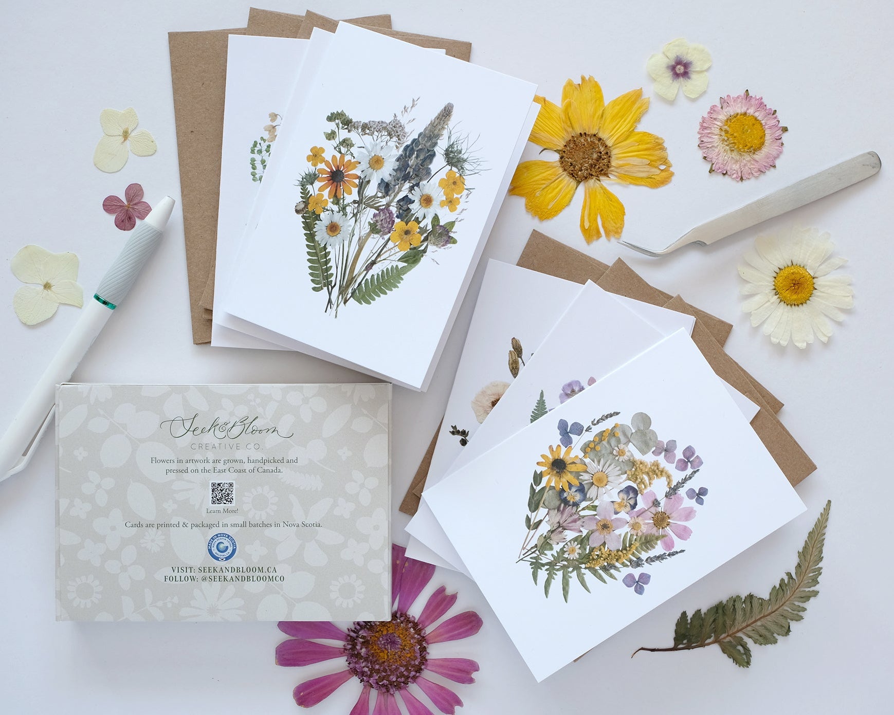 Collection of floral cards and stationery items on a light surface with flowers around.