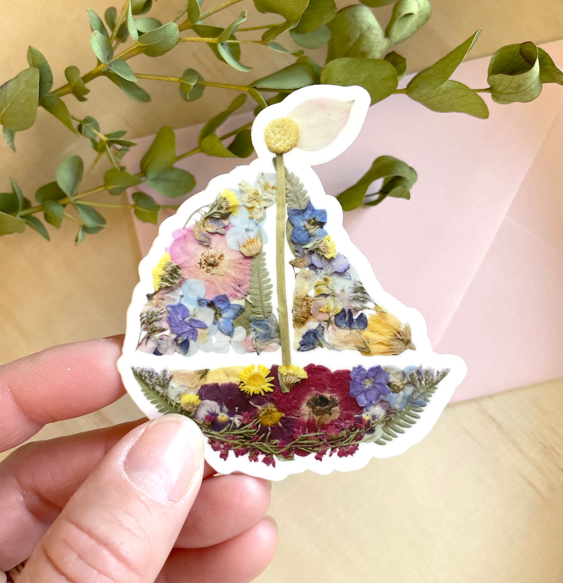 sticker of sailboat art made with colourful dried pressed flowers.