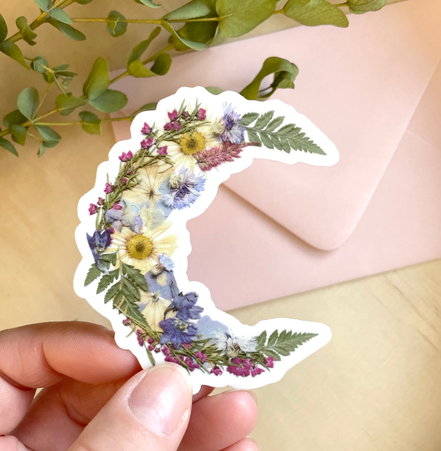 sticker of floral crescent moon made with dried pressed flowers. 