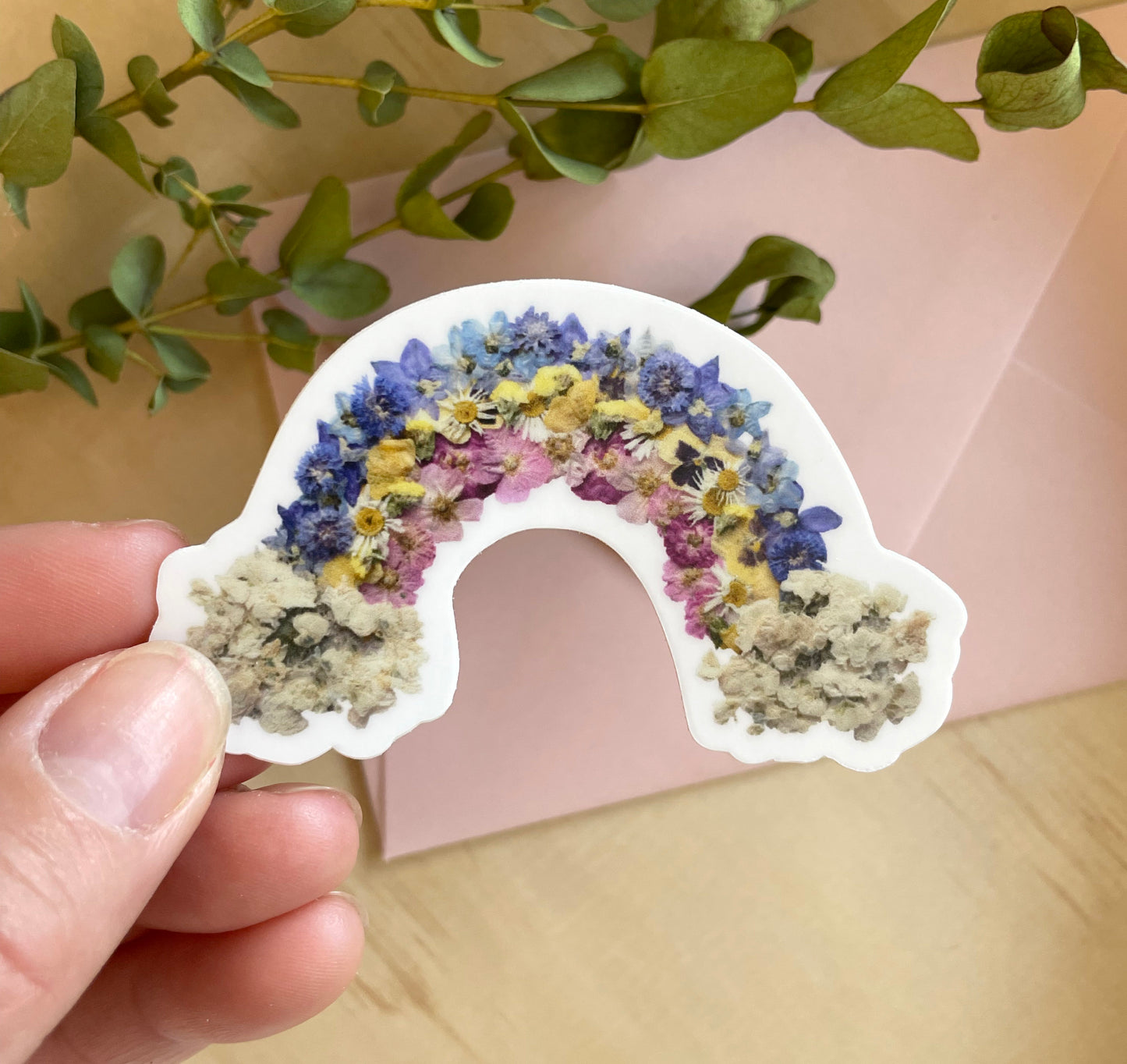 sticker of rainbow made from dried pressed flowers in the shape of a rainbow. 