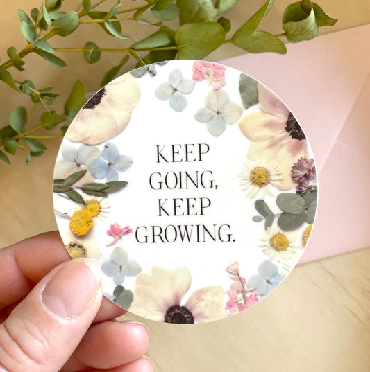 circle sticker of dried pressed flowers with quote keep going, keep growing. 