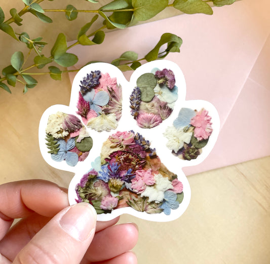 sticker of cute paw print made with pretty pressed flowers arranged like a paw print and printed on vinyl sticker.
